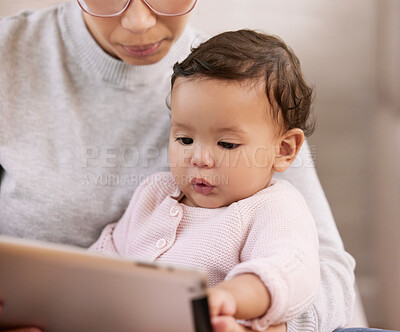 Buy stock photo Shot of a mother using a tablet with her baby at home