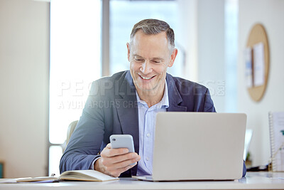 Buy stock photo Shot of a mature businessman using a phone and laptop in an office at work