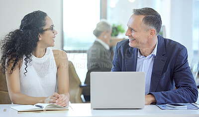 Buy stock photo Shot of two businesspeople using a laptop together in an office at work