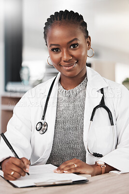 Buy stock photo Shot of a young doctor making notes at her desk