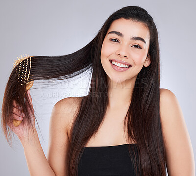Buy stock photo Studio portrait of an attractive young woman brushing her hair against a grey background