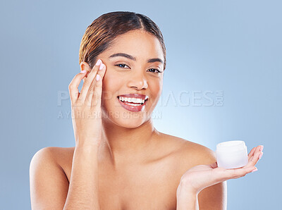 Buy stock photo Shot of a young woman applying lotion to her face against a grey background