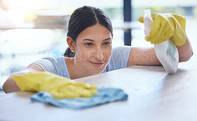 Buy stock photo Shot of a young woman smiling while cleaning a surface at home