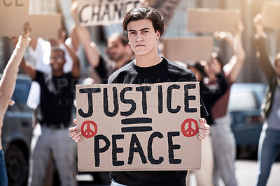 Buy stock photo Shot of a young man holding up a sign during a protest