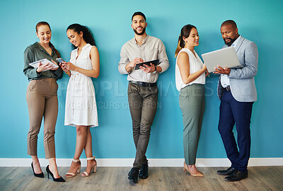 Buy stock photo Full length shot of a diverse group of businesspeople standing together in the office and using technology