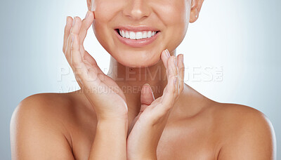 Buy stock photo Closeup of unknown woman smiling with white teeth after whitening treatment while touching face. Caucasian model isolated against grey studio background and showing perfect dental hygiene care routine