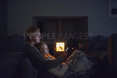 Buy stock photo A young couple cuddling at night while using a smartphone