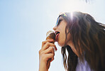 Woman eating ice cream on summer vacation. Low angle of girl having treat on beach