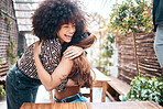 Cheerful friends hugging in a restaurant. Two women affectionately embrace. Happy friends in a cafe. Young friends being affectionate. Hispanic woman with curly afro hugging her friend.
