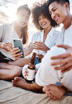 A group three  multiracial friends relaxing and using a phone at the beach while having alcoholic drinks