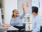 Two happy young call centre telemarketing agents giving each other a high five while cheering with joy in an office. Excited african american assistant celebrating with colleague on successful sales and reaching targets to win