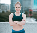 Portrait of one confident young caucasian woman standing with arms crossed ready for exercise outdoors. Determined female athlete looking happy and motivated for training workout in the city