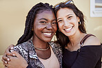 Portrait of two girls hugging and smiling while standing on sidewalk, feeling joyful and happy together. Multiethnic female friends in city