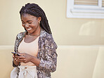 Happy african american woman using smartphone while walking on city street. Stylish woman smiling while sending a text or chatting on social media