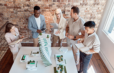 Buy stock photo Group of diverse architects discussing plans, blueprints and schematics during a meeting in their office boardroom. Business people brainstorming and planning their upcoming project development