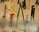 An arrangement of tools on a wooden wall. Closeup of a collection of tools hanging. Neat, tidy mechanics tools and equipment on a wall. Still life of tools in storage. Various tools in a workshop