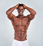 Portrait of a smiling African American fitness model posing topless in a underwear and looking muscular. Happy black male athlete isolated on grey copyspace in a studio wearing boxers