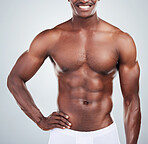 Closeup of a smiling African American fitness model posing topless in a towel and looking muscular. Happy black male  athlete isolated on grey copyspace in a studio after a shower