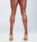 Closeup of one  African American fitness model posing and looking muscular. Confident black male athlete isolated on grey copyspace in a studio showing his strong, toned calves