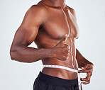 One unrecognizable African American fitness model posing topless with tape measure around his waist . Confident male athlete isolated on grey copyspace showing thumbs up to weight loss