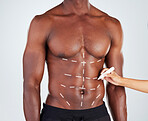 Closeup of an unrecognizable African American fitness model getting marked for a medical procedure.  Confident black male athlete isolated on grey copyspace in a studio before liposuction