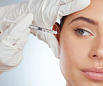 Closeup of woman getting facial fillers or botox. Young caucasian model isolated against a grey studio background with copyspace. Dermatologist injecting patient during anti ageing cosmetic procedure