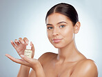 Portrait of beautiful woman holding face serum while posing with copyspace. Young caucasian model isolated against grey studio background. Using skin oil for healthy glowing skin for skincare routine