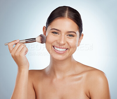 Buy stock photo .Portrait of beautiful woman using cosmetic makeup brush to apply blush makeup while posing with copyspace. Caucasian model isolated against grey studio background. Getting ready after skincare routine