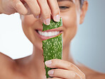 Closeup of smiling beautiful woman holding aloe vera leaf for her skincare routine. Caucasian model isolated against grey studio background and posing. Using organic plants for hydration and moisture