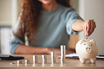 Young african american woman money putting coins into a piggybank at home. Mixed race person counting coins while financial planning in her living room. Saving, investing and thinking about the future
