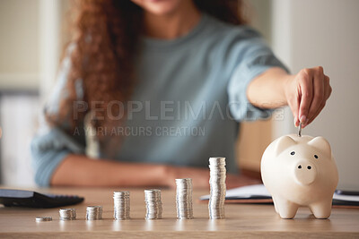 Buy stock photo Young african american woman money putting coins into a piggybank at home. Mixed race person counting coins while financial planning in her living room. Saving, investing and thinking about the future