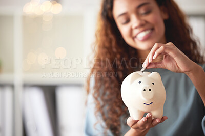Buy stock photo One happy young mixed race woman holding a piggybank and depositing a coin as savings. Hispanic woman budgeting her finances and investing money into her future. Saving funds for financial freedom