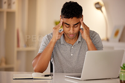 Buy stock photo Young stressed man working alone on a laptop in an office at night. Guy looking tired and worried while struggling with burnout and a headache from problems, deadlines and pressure at work