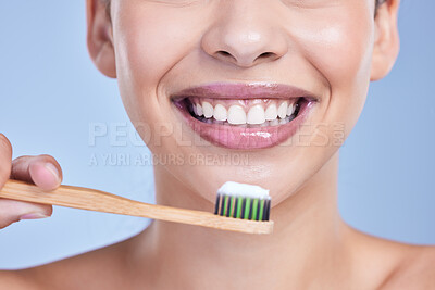 Buy stock photo Closeup of a smiling mixed race young woman with glowing skin posing against blue copyspace background while brushing her teeth for fresh breath. Hispanic model using toothpaste to prevent a cavity