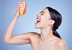 A  happy mixed race woman holding a grapefruit. Hispanic model promoting the skin benefits of citrus diet against a blue copyspace background