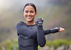 Beautiful young mixed race woman stretching outside on a foggy morning. Confident female athlete warming up before a workout in the mountains. Exercise daily. Cardio will increase your endurance