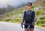 One athletic young woman cycling outside. Sporty fit female wearing a helmet and glasses while riding a bike along the mountain for exercise. Smiling and looking happy to be enjoying a hobby