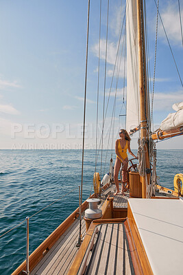 Buy stock photo Content young woman in yellow swimsuit looking at the ocean steering a boat on cruise. Young woman in yellow swimsuit steering a boat on holiday cruise in Italy. Woman steering boat looking at ocean
