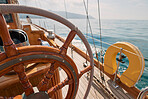 Closeup of wooden steering wheel on empty boat sailing the ocean. Closeup of empty boat deck with rigging cables wooden steering wheel sailing the ocean.