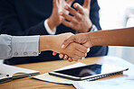 Coworkers shaking hands while their colleague claps hands. Group of businesspeople having a meeting at a table in an office. Business professionals planning and making deals together at work