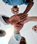 Group of doctors stacking their hands together in support while working at a hospital. Medical professionals piling their hands in unity and motivation while working at a clinic
