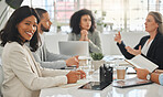 Portrait of a young african american businesswoman sitting in a meeting at work. Group of businesspeople having a meeting together at a table. Business professionals talking and planning in an office