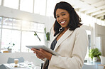 Young happy african american businesswoman working on a digital tablet alone in an office. One confident black female boss smiling and holding a digital tablet at work