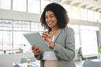 Young happy mixed race businesswoman working on a digital tablet in an office. One cheerful hispanic female boss with a curly afro holding and using social media on a digital tablet at work