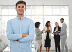 Young happy caucasian businessman standing with his arms crossed while in an office with colleagues. Content male boss In a meeting with coworkers
