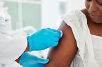 Patient looking at a doctor cleaning her arm. African american woman having her arm cleaned with a cotton ball. Hand of a doctor wiping the arm of a patient with a cotton ball.