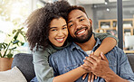 Portrait of a happy mixed race couple embracing while relaxing at home. Hispanic boyfriend and girlfriend smiling while spending time together in the lounge at home