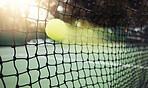 Closeup of one yellow tennis ball with motion blur hitting a net during a game on a court. Fast ball moving with speed during a competitive sports match in a sports club. Losing by touching the net