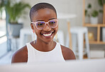 Young african american businesswoman wearing glasses, smiling and working on a computer in an office. One female only browsing online while planning on a desktop pc at her desk. Confident hard working black female entrepreneur completing deadlines and se