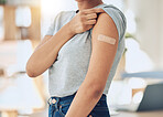 Unrecognizable woman wearing and showing a bandaid on her arm after getting a vaccine at a hospital. One unrecognizable woman standing with a plaster on her arm after getting a covid vaccine